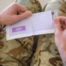 Soldier's hands opening payslip envelope