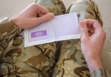 Soldier's hands opening payslip envelope
