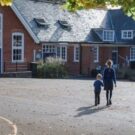 Two schoolchildren walking across a playground